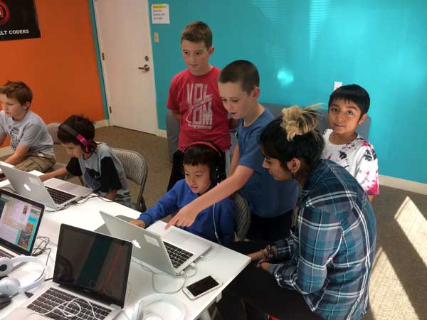 An instructor helping a group of students with their code at Hackingtons Pleasant Hill