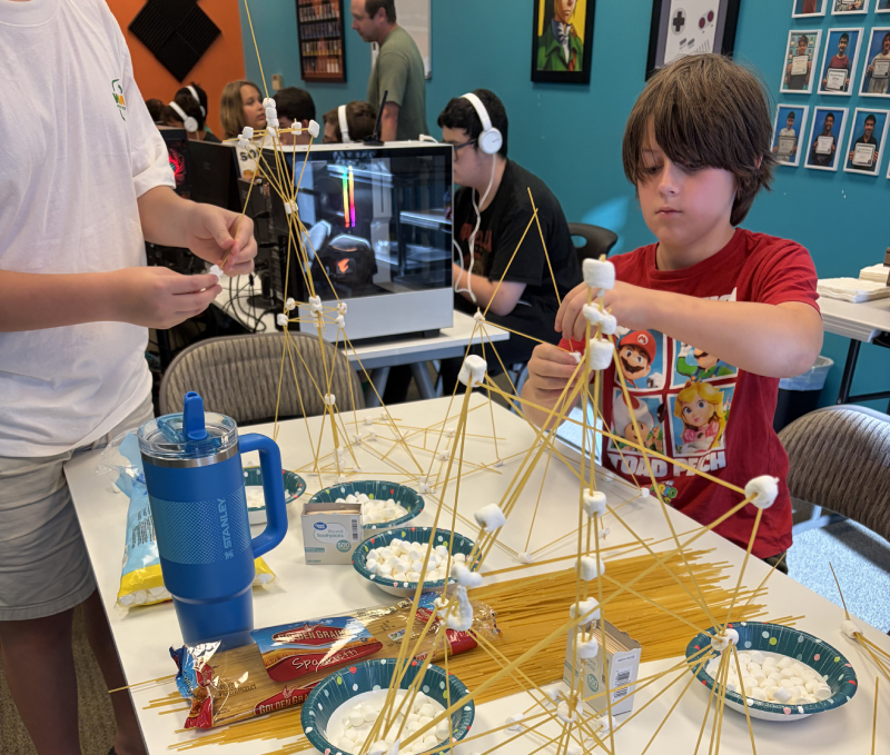 Students building a spaghetti and marshmallow tower at the Hackingtons Rocklin anniversary party