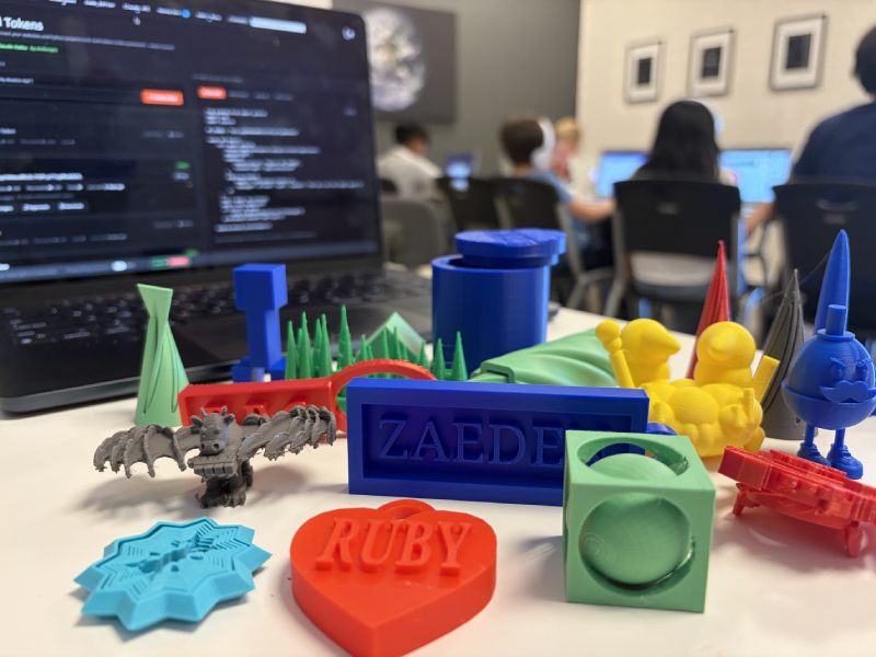 Colorful 3D printed projects made by Hackingtons students, including name tags, characters, and puzzles
